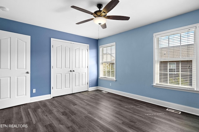 unfurnished bedroom with dark wood-style floors, a closet, visible vents, and baseboards