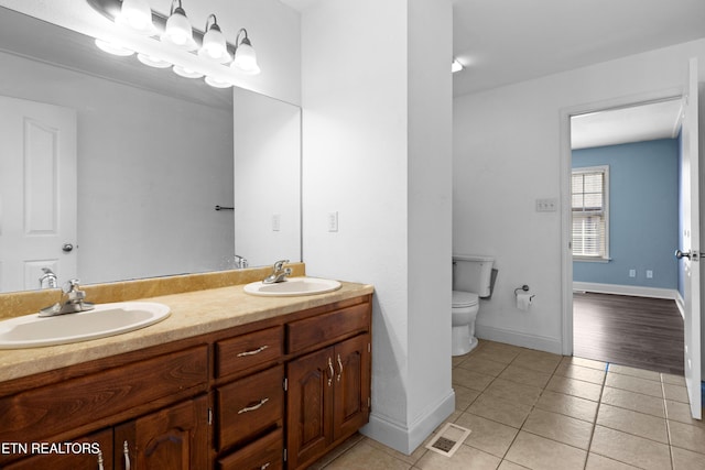 bathroom featuring toilet, a sink, visible vents, and tile patterned floors