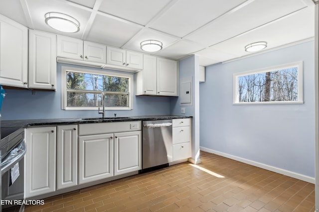 kitchen featuring brick floor, appliances with stainless steel finishes, white cabinetry, a sink, and baseboards