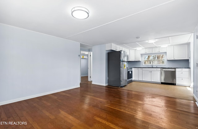 kitchen with appliances with stainless steel finishes, dark wood-type flooring, dark countertops, and white cabinetry