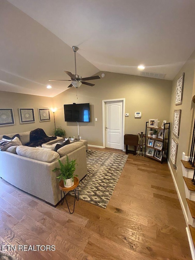 living room featuring vaulted ceiling, wood finished floors, baseboards, and ceiling fan