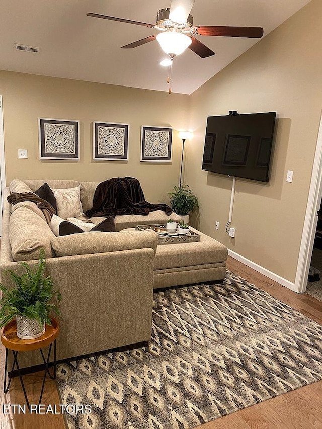 living area featuring wood finished floors, baseboards, visible vents, ceiling fan, and vaulted ceiling