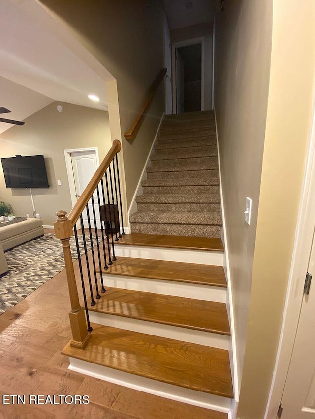 stairway featuring baseboards, wood finished floors, and vaulted ceiling