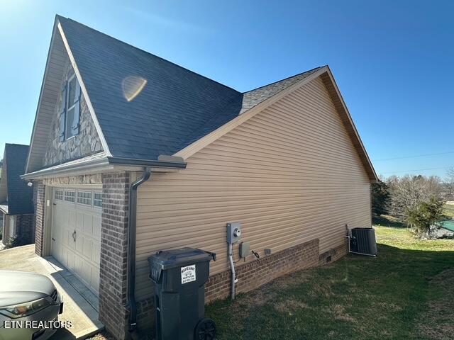 view of property exterior featuring central air condition unit, a lawn, and a garage