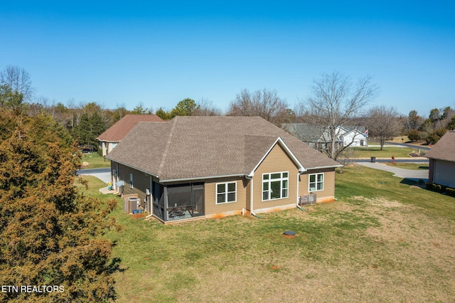 back of house featuring roof with shingles, a lawn, a sunroom, and central air condition unit