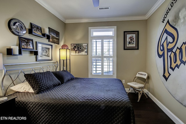 bedroom with baseboards, wood finished floors, visible vents, and crown molding