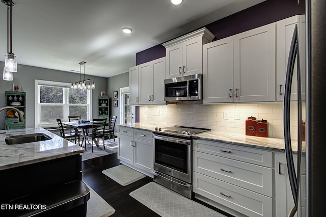 kitchen featuring decorative backsplash, appliances with stainless steel finishes, dark wood-type flooring, white cabinetry, and a sink