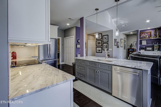 kitchen featuring appliances with stainless steel finishes, a sink, visible vents, and light stone countertops