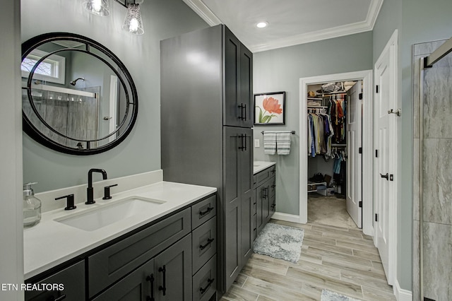 bathroom featuring a shower stall, wood tiled floor, ornamental molding, and vanity