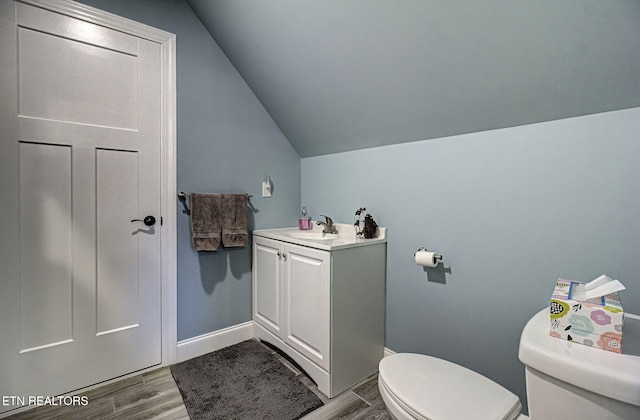 half bath featuring toilet, lofted ceiling, a sink, and wood finished floors