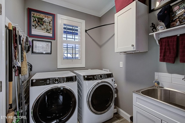 washroom with a sink, baseboards, washer and dryer, ornamental molding, and cabinet space