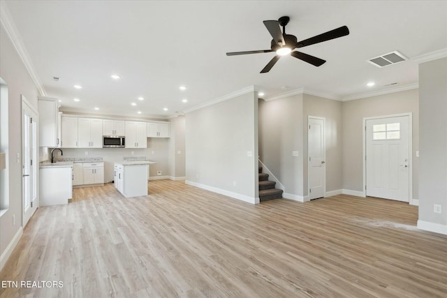 unfurnished living room with light wood finished floors, recessed lighting, visible vents, stairway, and baseboards