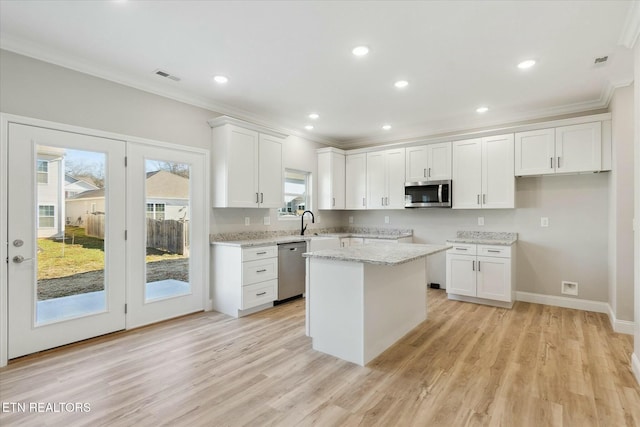 kitchen with stainless steel appliances, light wood-style floors, ornamental molding, white cabinetry, and light stone countertops