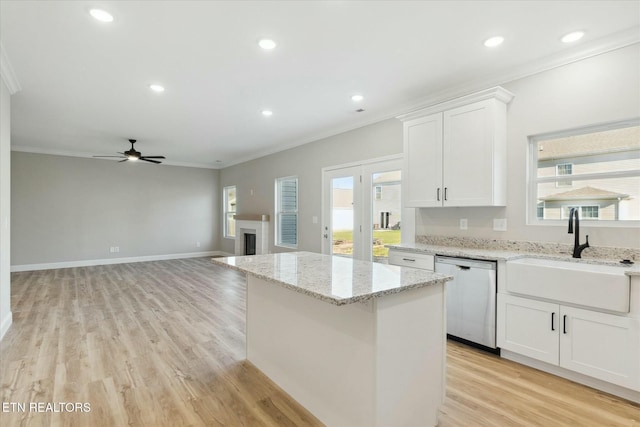 kitchen with white cabinets, dishwasher, ornamental molding, a fireplace, and a sink