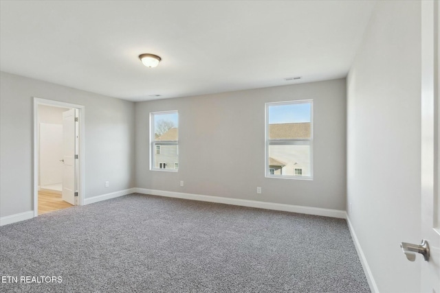 carpeted spare room with visible vents and baseboards