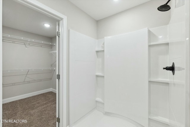 full bath featuring a shower, a spacious closet, and baseboards