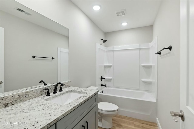 bathroom with toilet, vanity, wood finished floors, and visible vents