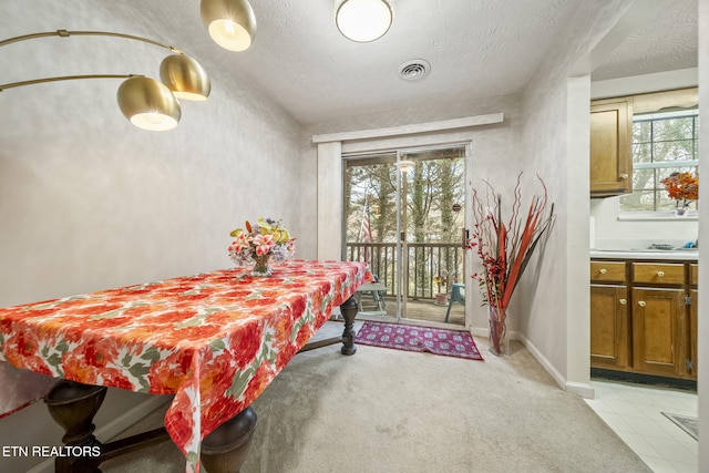 dining space with a textured ceiling, light tile patterned floors, visible vents, and baseboards