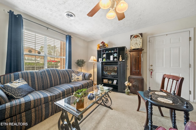 carpeted living room featuring ceiling fan, visible vents, and a textured ceiling