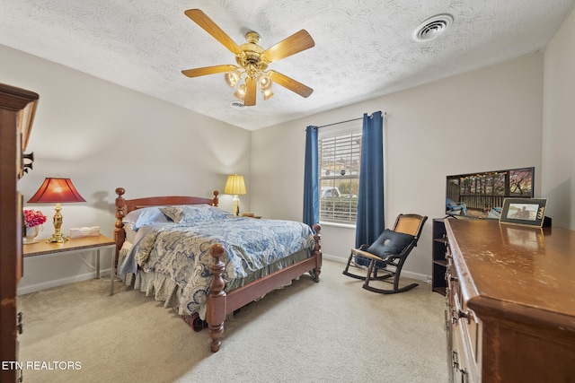 carpeted bedroom with baseboards, visible vents, ceiling fan, and a textured ceiling