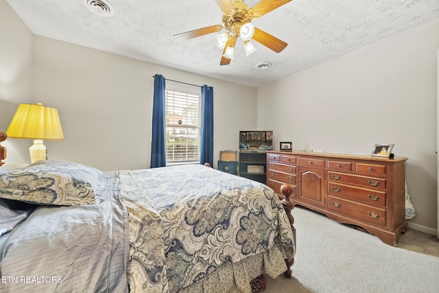 bedroom featuring a textured ceiling, a ceiling fan, visible vents, and light colored carpet