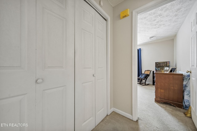 hallway featuring carpet flooring, a textured ceiling, and baseboards