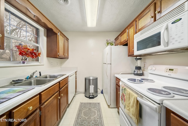 kitchen with white appliances, brown cabinets, a sink, and light countertops