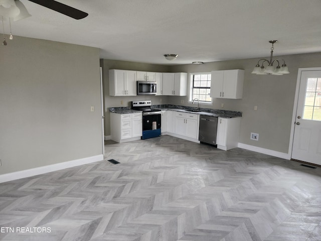 kitchen featuring appliances with stainless steel finishes, white cabinetry, a sink, and baseboards