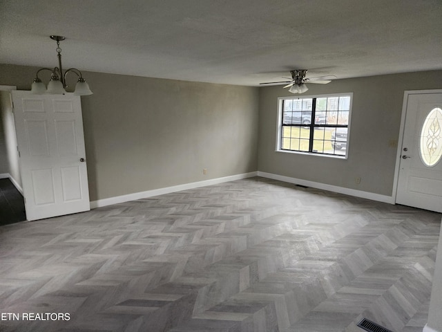 entrance foyer featuring visible vents, baseboards, a textured ceiling, and ceiling fan with notable chandelier