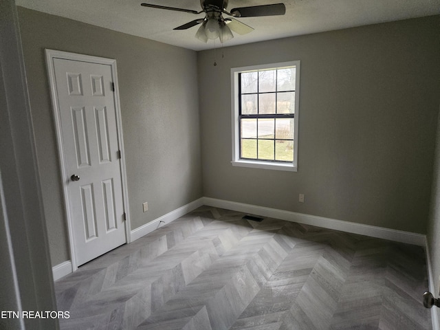 unfurnished room featuring a ceiling fan and baseboards