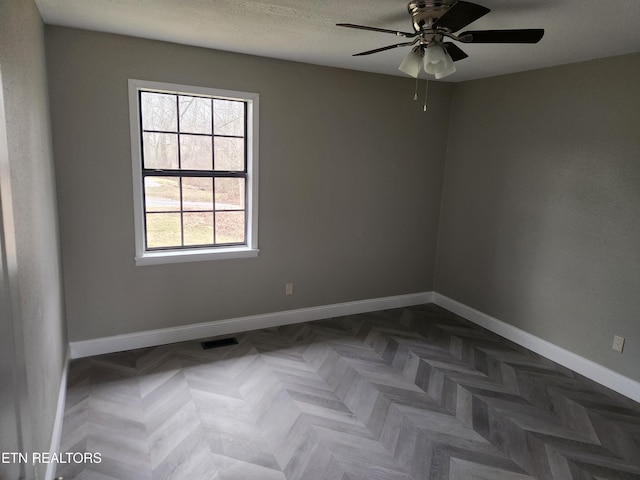 unfurnished room featuring a ceiling fan, visible vents, baseboards, and a textured ceiling