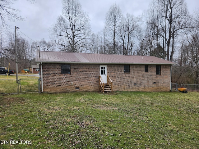 rear view of house with entry steps, crawl space, brick siding, and metal roof