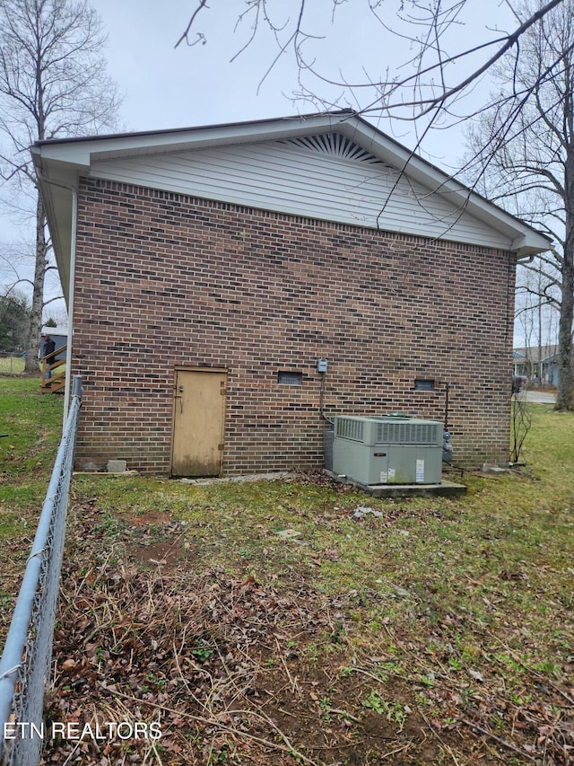 view of property exterior featuring crawl space, brick siding, a lawn, and central AC unit