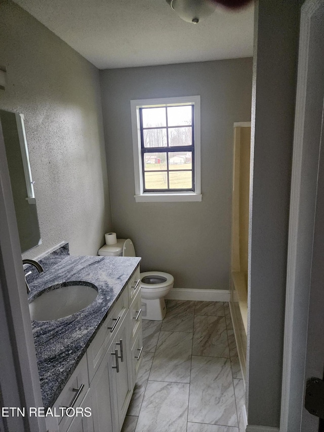 bathroom with a shower, marble finish floor, toilet, vanity, and baseboards