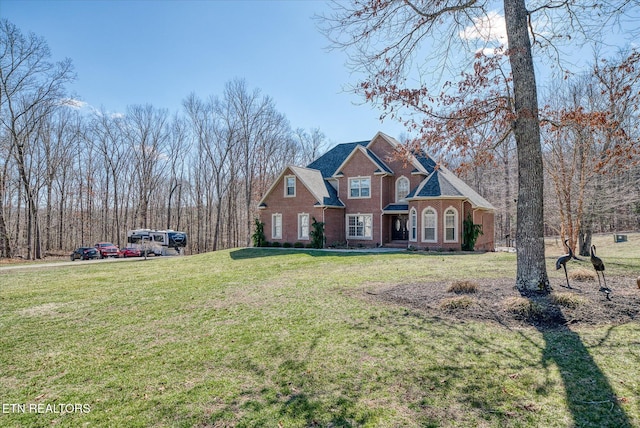 view of front of home with brick siding, a front lawn, and roof with shingles