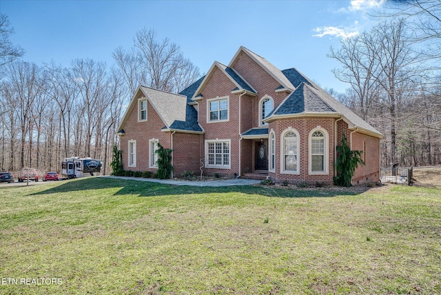 view of front of home with a shingled roof, brick siding, and a front lawn