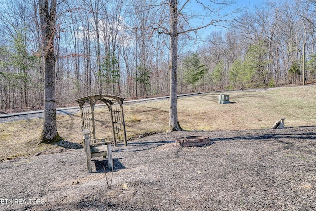 view of yard with an outdoor fire pit and a forest view