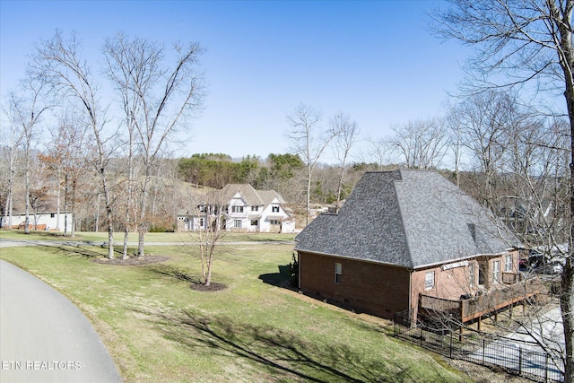 exterior space with brick siding, a shingled roof, a lawn, crawl space, and fence