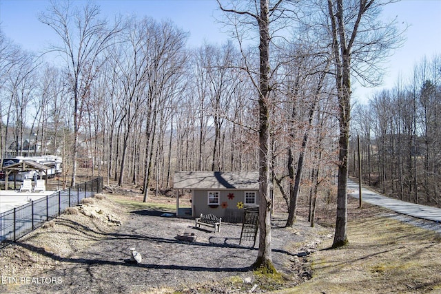 exterior space featuring an outbuilding, fence, and a wooded view