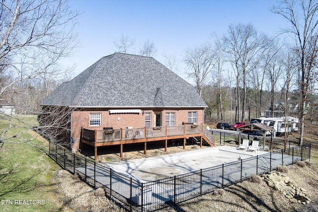 rear view of property with a fenced in pool, brick siding, a shingled roof, fence, and a deck