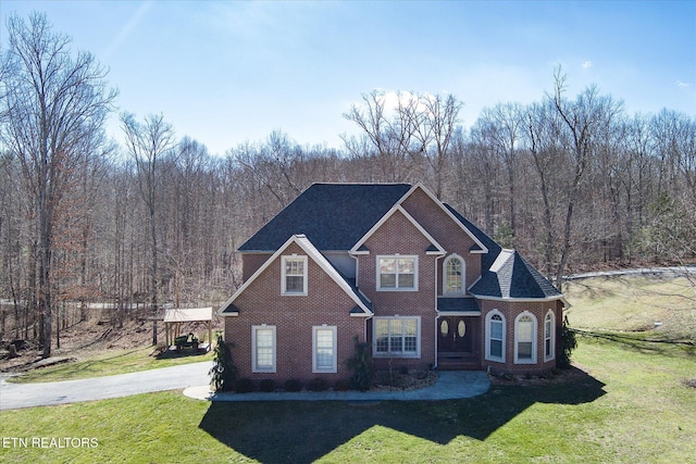 traditional-style home with brick siding, a view of trees, and a front yard