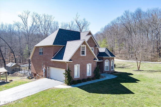 view of front of house with driveway, a view of trees, an attached garage, a front lawn, and brick siding