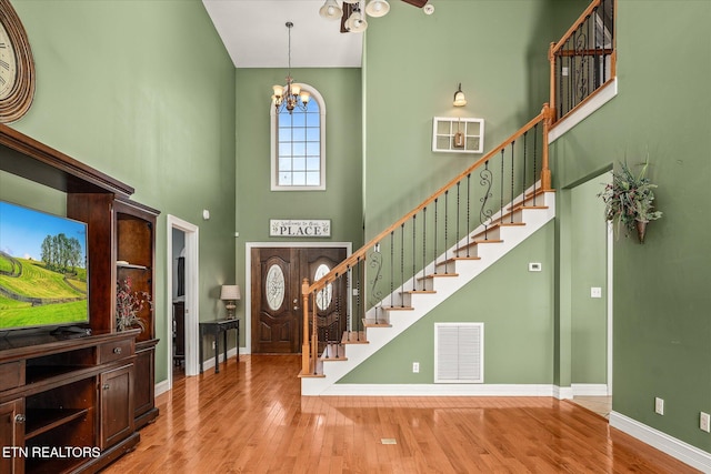 foyer featuring stairs, wood finished floors, visible vents, and a notable chandelier