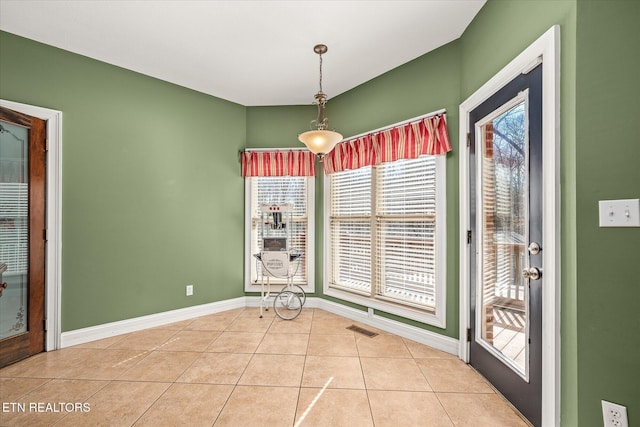 unfurnished dining area featuring baseboards, visible vents, and tile patterned floors