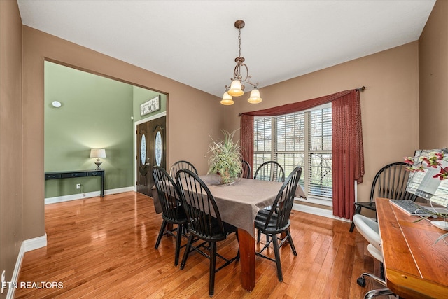 dining room featuring light wood-style floors, baseboards, and an inviting chandelier