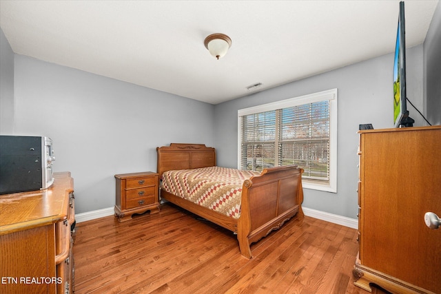 bedroom featuring light wood-style floors, visible vents, and baseboards