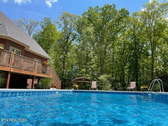 pool featuring stairs, a wooden deck, and fence