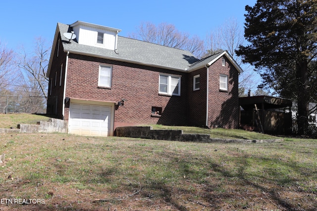 back of property featuring brick siding, an attached garage, and a yard