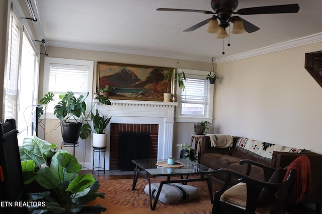 living area with a brick fireplace, crown molding, ceiling fan, and wood finished floors