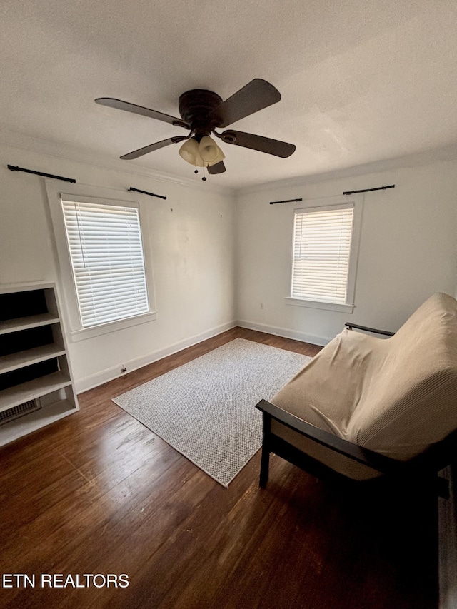 sitting room with a textured ceiling, crown molding, baseboards, and wood finished floors